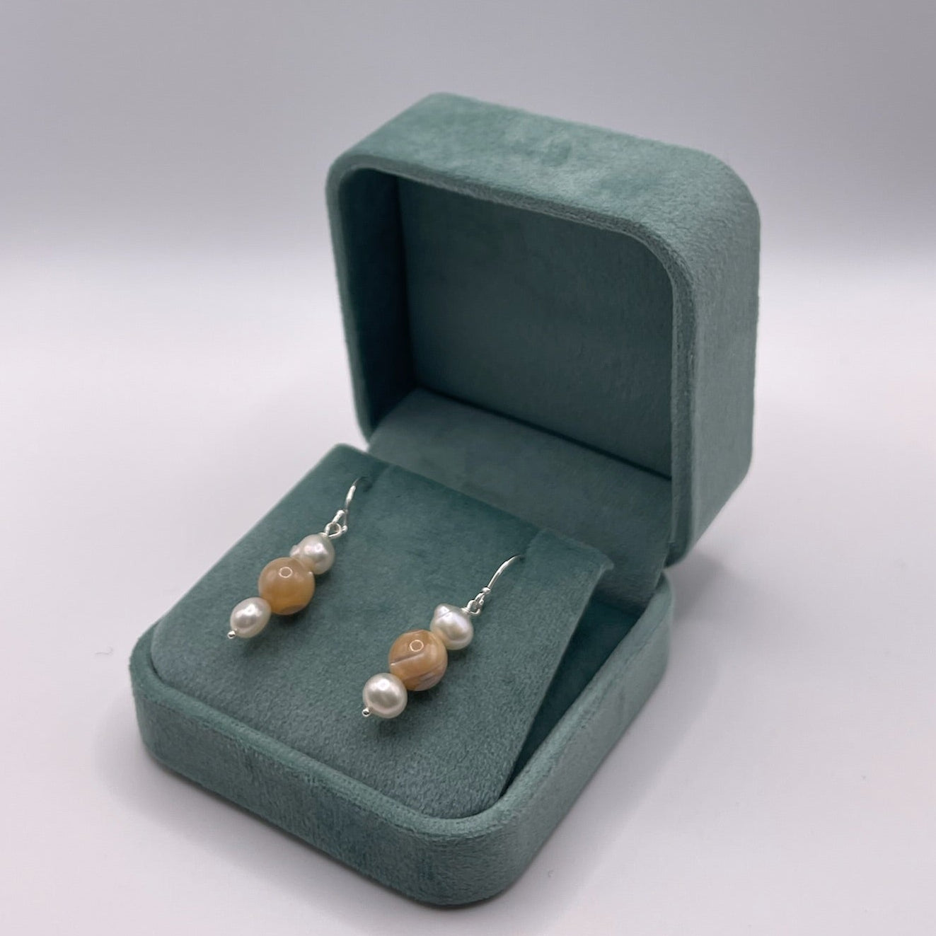 Pair of earrings in a green jewelry box on a white background