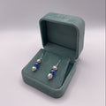 Pair of earrings with blue and white pearls on a light gray background
