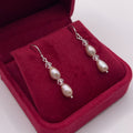 Pearl earrings in a red jewelry box on a white background