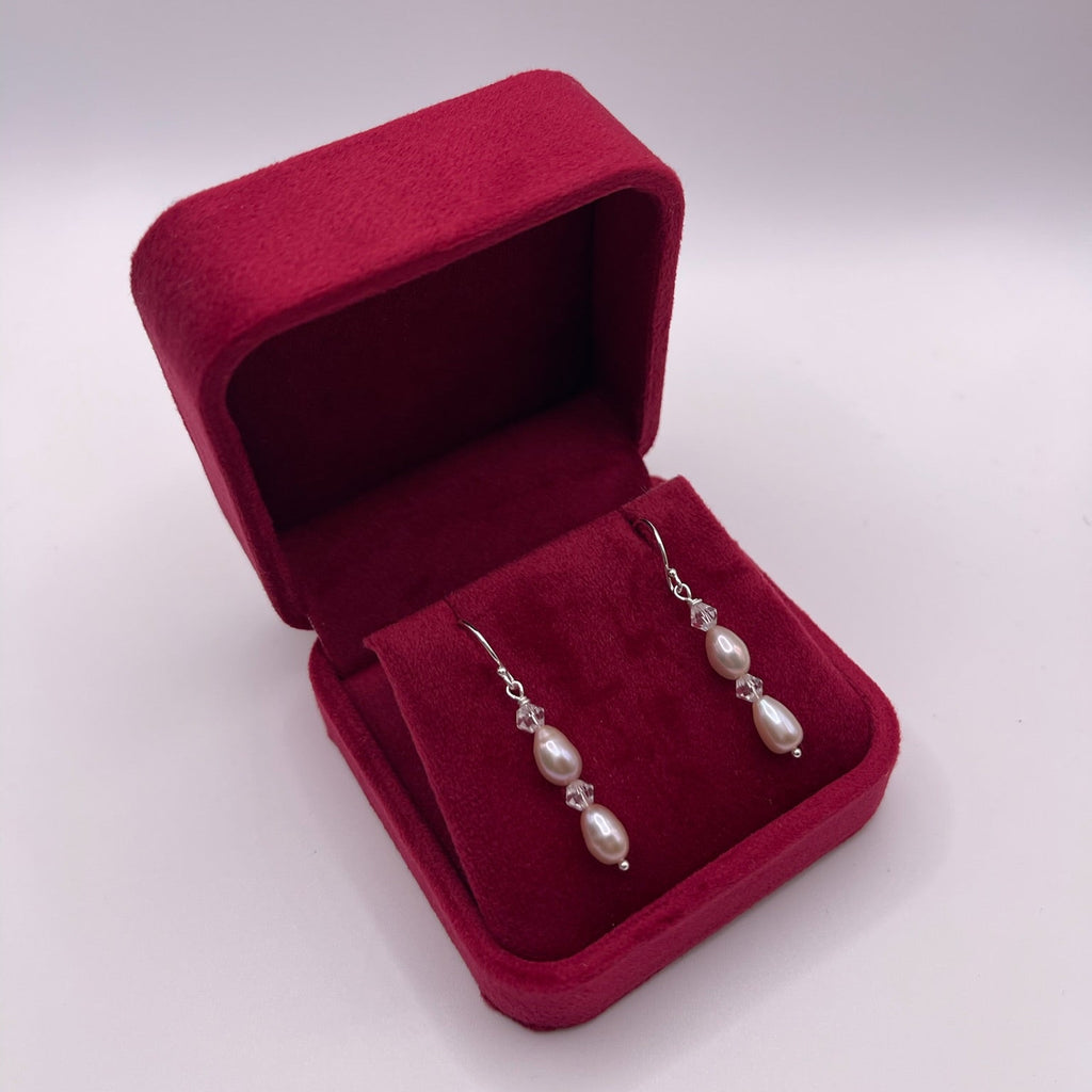 Pearl earrings in a red jewelry box on a white background